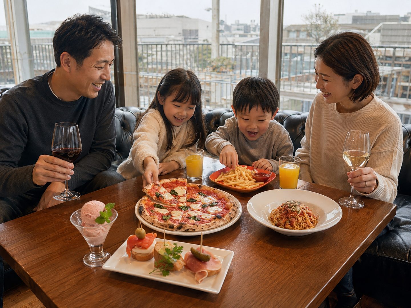 窓際の席で、石窯ピザやパスタを囲んで食事を楽しむ家族4人
